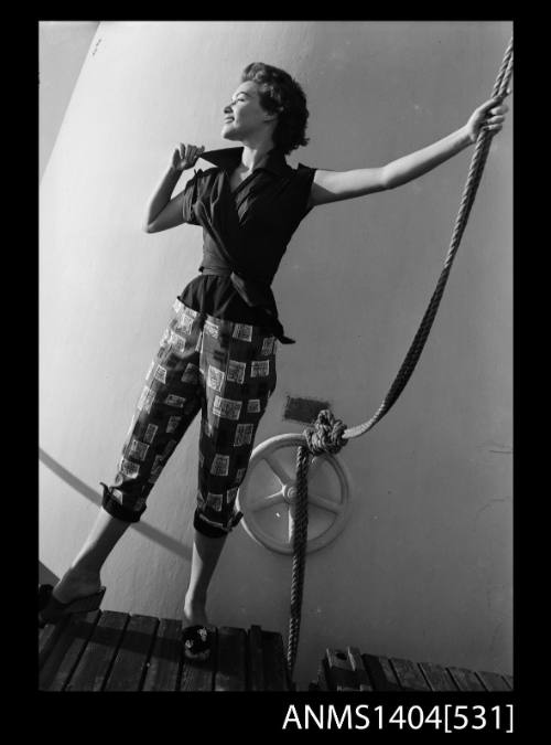 Photographic negative of a model posing in a shirt and pants on a ship