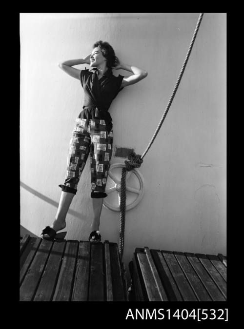 Photographic negative of a model posing in a shirt and pants on a ship