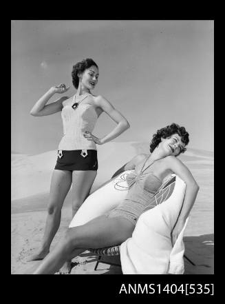 Photographic negative of two swimsuit models posing on a sand dune