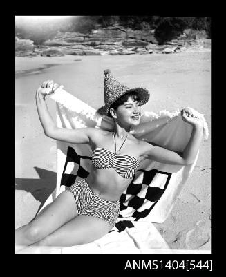 Swimsuit model posing in a bikini with a beach towel and hat