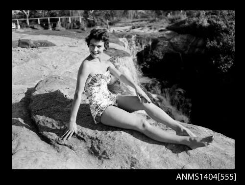 Photographic negative of a swimsuit model posing on rocks