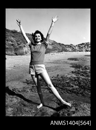 Photographic negative of a model in a t-shirt and shorts on a beach