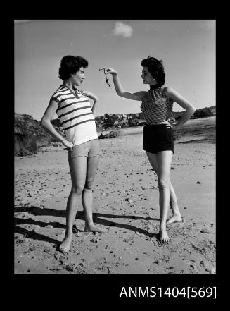 Photographic negative of two models in casual wear on a beach