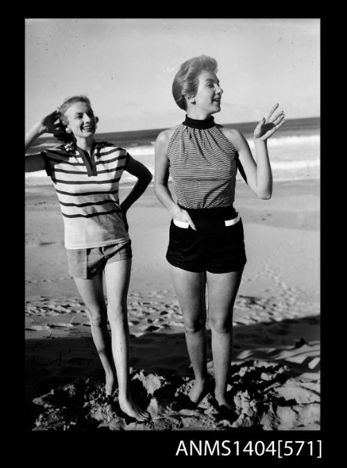 Photographic negative of two models in casual wear posing on a beach