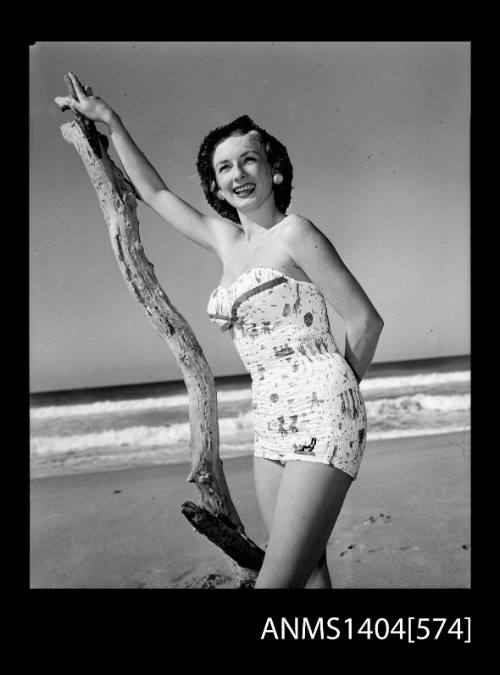 Photographic negative of a swimsuit model posing on a beach with a tree