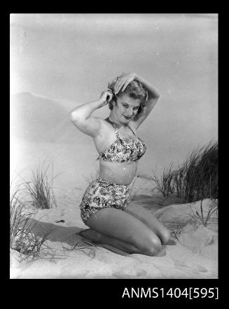 Photographic negative of a swimsuit model posing on a sand dune