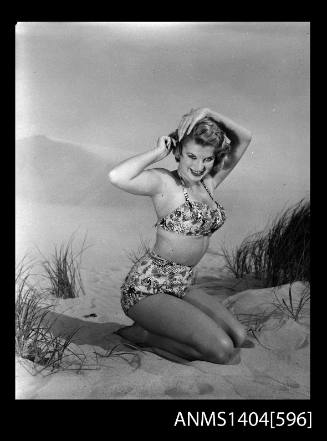 Photographic negative of a swimsuit model posing on a sand dune