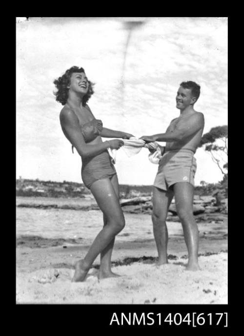 Photographic negative of a man and woman modelling swimwear on a beach