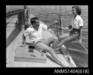 Photographic negative of a man and woman modelling casual wear on a boat