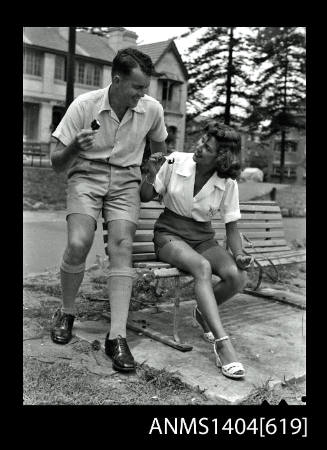 Photographic negative of a man and woman modelling casual wear on a park bench