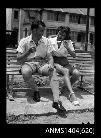 Photographic negative of a man and woman modelling casual wear on a park bench