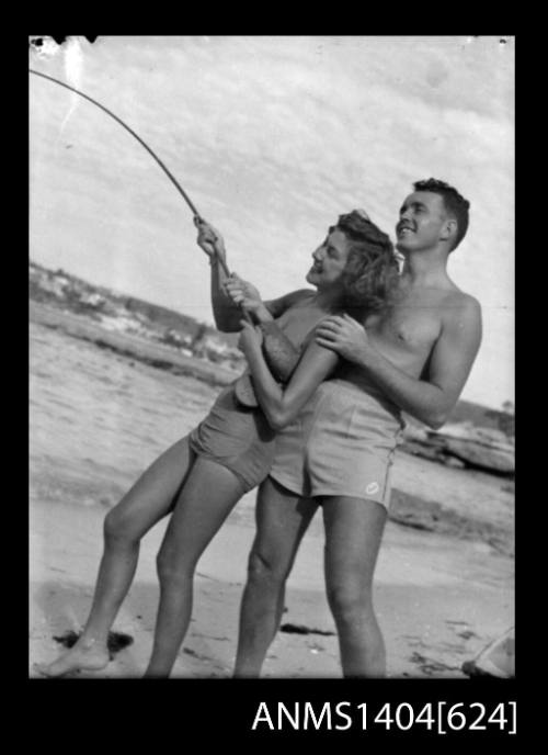 Photographic negative of a man and woman modelling swim wear on a beach