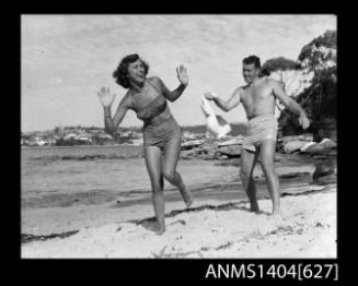 Photographic negative of a man and woman modelling swimwear on a beach