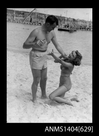 Photographic negative of a man and woman modelling swimwear at the beach