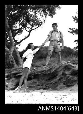 Photographic negative of a man and woman modelling casual wear on a beach