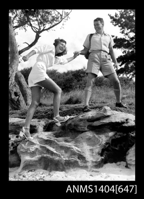 Photographic negative of a man and woman modelling casual wear on a rocky beach