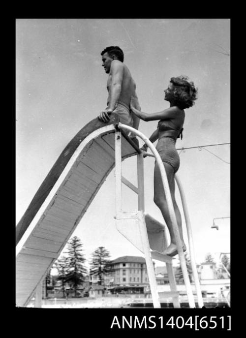 Photographic negative of a man and woman modelling swim wear on a slide