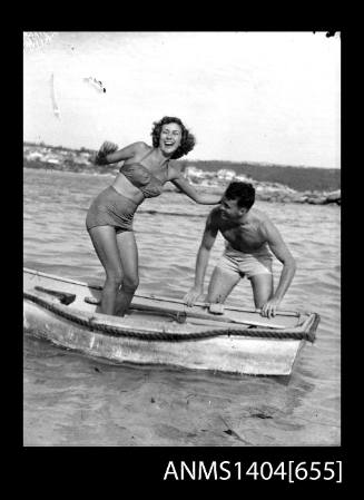 Photographic negative of a man and woman modelling swim wear on a small boat