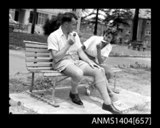 Photographic negative of a man and woman modelling casual wear on a park bench