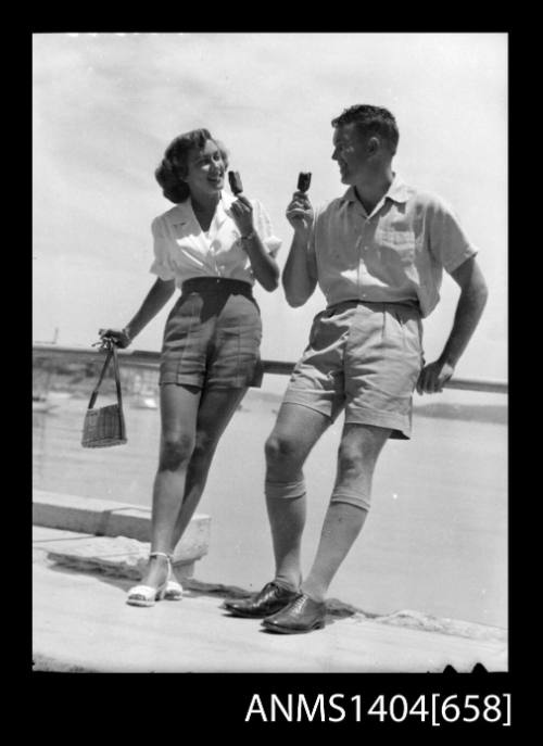 Photographic negative of a man and woman modelling casual wear on a promenade eating icecream