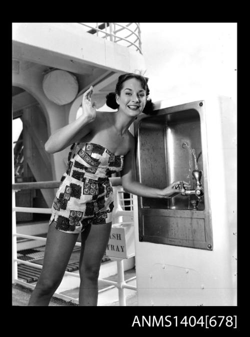 Photographic negative of a swimsuit model posing on a ship with a drinking fountain