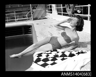 Photographic negative of a swimsuit model posing on a ship