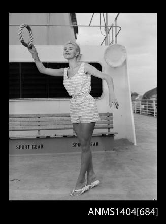 Photographic negative of a model playig quoits on the deck of a ship