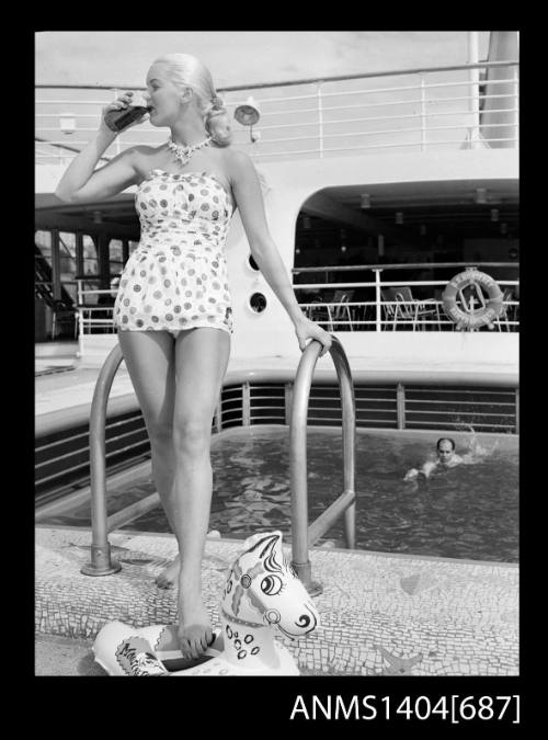 Photographic negative of a swimsuit model posing on a ship in front of the pool