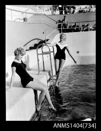 Photographic negative of a two models posing in a pool on a ship