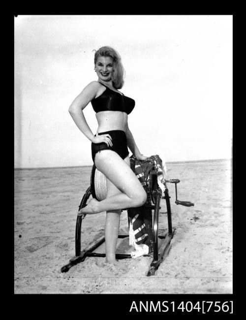 Photographic negative of a swimsuit model posing on a sand dune with a surf reel