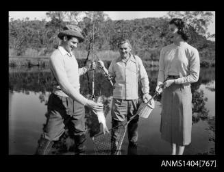 Photographic negative of two men and a woman fishing in a river