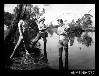 Photographic negative of two men and a woman fishing in a river