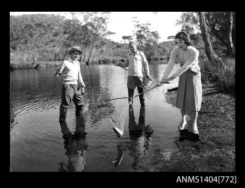 Photographic negative of two men and a woman fishing in a river