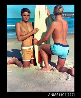 Photographic transparency of two teengage buys in swimwear at the beach with a surfboard