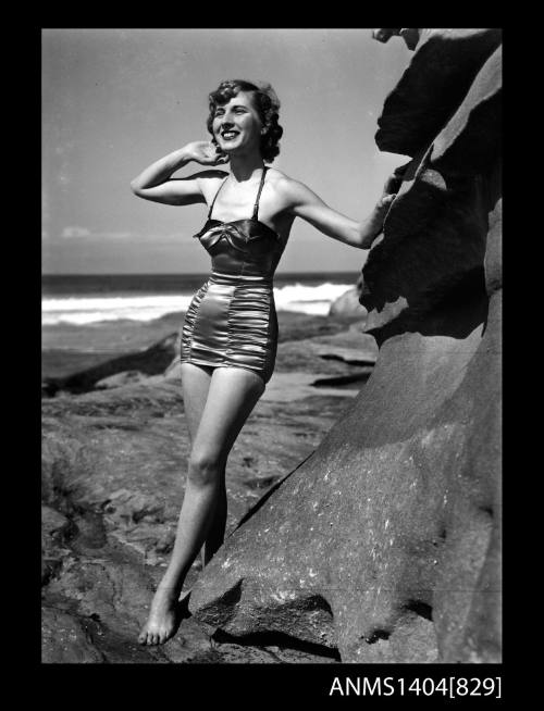 Photographic negative of a swimsuit model posing on a rock