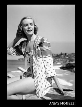 Photographic negative of a swimsuit model posing on a fence