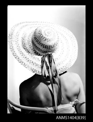 Photographic negative of a model posing with a hat