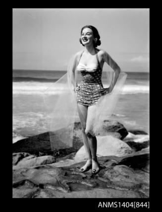 Photographic negative of a swimsuit model posing on a rock