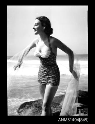 Photographic negative of a swimsuit model posing on a rock