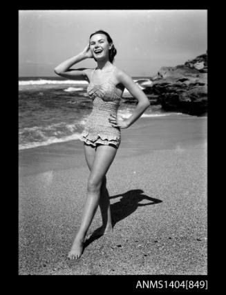 Photographic negative of a swimsuit model posing on a rock