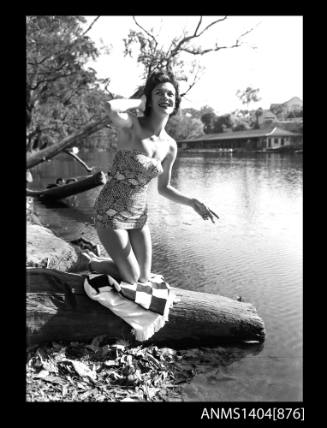 Photographic negative of a swimsuit model posing on a river bank