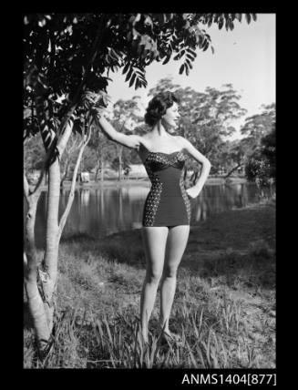 Photographic negative of a swimsuit model posing on a river bank