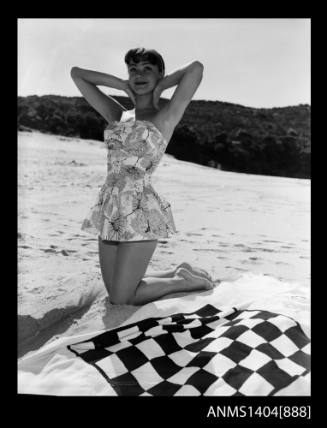 Photographic negative of a swimsuit model posing on a sand dune