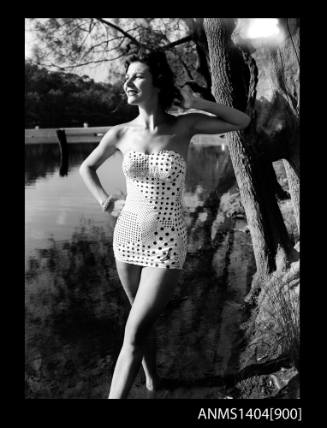 Photographic negative of a swimsuit model posing on a river bank