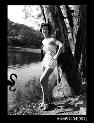 Photographic negative of a swimsuit model posing on a river bank