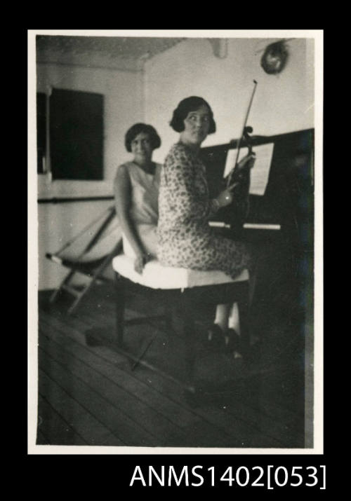 Two female passengers seated at a piano, one with a violin (E & A Line)