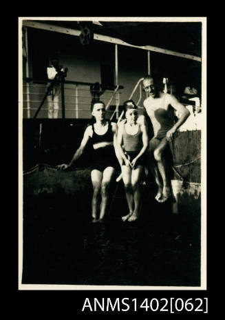 Two men and a boy seated on the side of the swimming pool (E & A Line)