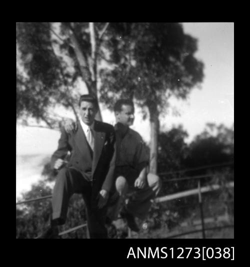 Two men sitting on a fence, one of the men being Denis George