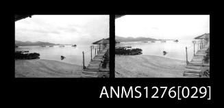 Two black-and-white negatives, joined together, of a a beach, with a wooden walkway to a shed over the water