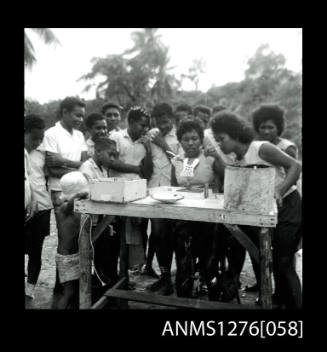 Standing around a table watching a person seed a pearl shell on Pearl Island